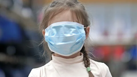 Portrait of a 6-7 year old girl who jokingly pulled on a boring medical mask Stock Footage 146313145