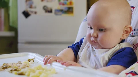 Portrait of 9 month old chubby baby in the kitchen. Little baby sits Stock Footage 129702190