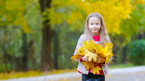 Portrait of adorable little girl with yellow and orange leaves bouquet outdoors Stock Footage