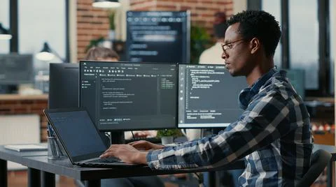 Portrait of african american developer using laptop to write code sitting at Stock Photos
