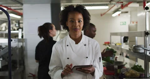 Portrait of african american female chef holding tablet looking at camera and Stock Footage