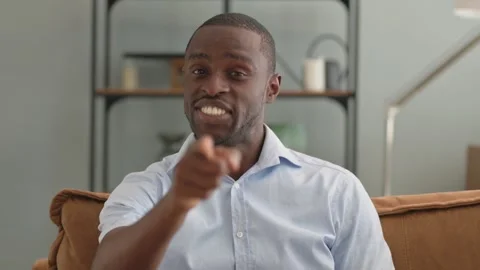 Portrait of African Man Pointing at Camera Sitting on Sofa at Home Stock Footage 287918693