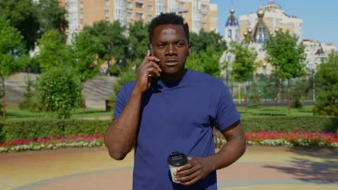 Portrait Afro-American man talking on mobile phone drinking coffee tea in summer Stock Footage 161535053
