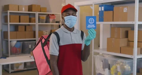 Portrait of afro courier in safety mask and gloves looking at camera holding Stock Footage 243641553