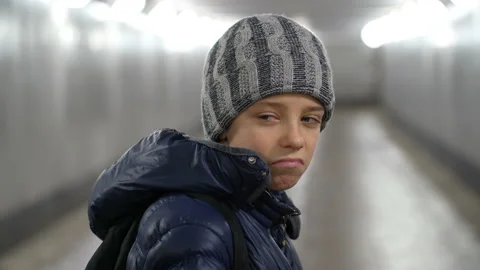Portrait of alone sad boy in hat and jacket in underground covered walkway in Stock Footage 169745353