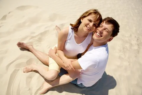 Portrait of amorous couple embracing while sitting on sand Fotos Stock