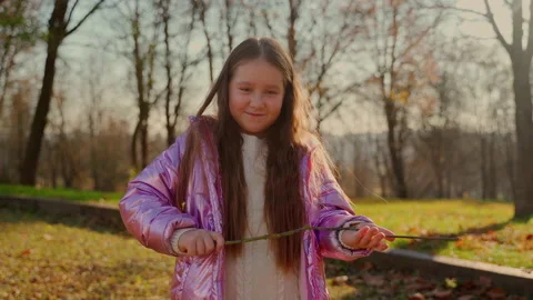 Portrait angry child looking at camera in autumn park. Person show tree branch Stock Footage 164733964
