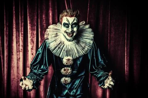 A portrait of an angry crazy clown from a horror film over the red curtain. H Stock Photos