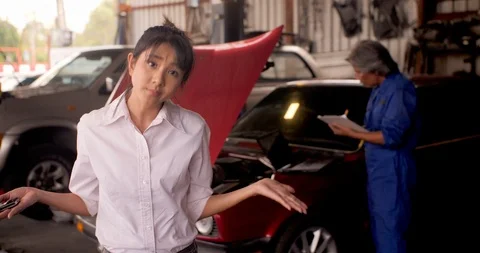 Portrait of angry customer while a mechanic works on a car in the background. Видео 93437070