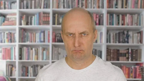 Portrait angry man face looking into camera on bookcase background Stock Footage 87612109