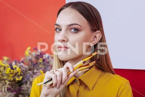 Portrait of appealing blonde-haired artist holding painting brushes Stock Photos