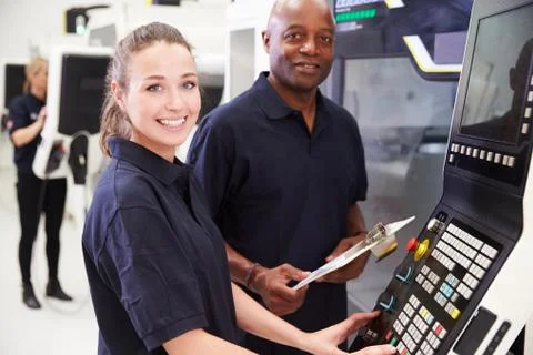 Portrait Of Apprentice Working With Engineer On CNC Machine Foto stock