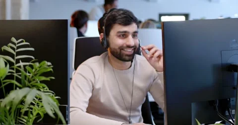 Portrait of Arabian handsome man in headset working at computer screen, talking Stock Footage 179986357