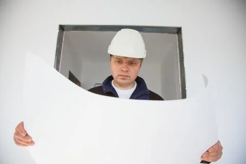 Portrait of an architect builder studying layout plan of the rooms Stockfoto's