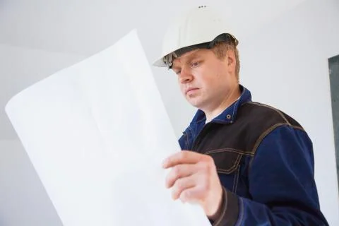 Portrait of an architect builder studying layout plan of the rooms Фото