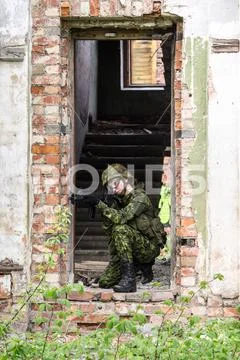 Portrait of armed woman with camouflage. Young female soldier observe with fi Stock Photos