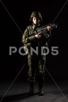 Portrait of armed woman with camouflage. Young female soldier observe with fi Stock Photos