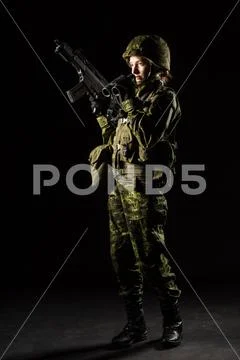 Portrait of armed woman with camouflage. Young female soldier observe with bi Stock Photos