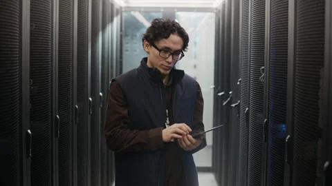 Portrait of Asian Data Center Engineer Holding Tablet in Server Corridor Stock Footage 330545230
