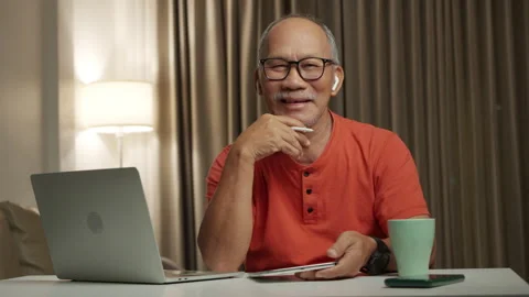 Portrait of Asian Elderly man smiling while using tablet indoors, wearing Stock Footage 303699558
