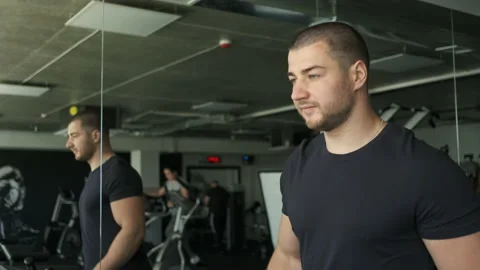 Portrait of an athletic guy with big biceps warming up on a treadmill before a Stock Footage 134577003