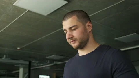 Portrait of an athletic guy with big biceps warming up on a treadmill before a Stock Footage 134988751