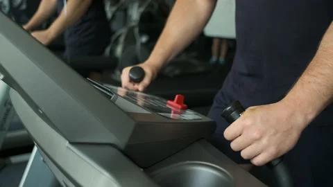 Portrait of an athletic guy with big biceps warming up on a treadmill before a Video stock 135591547