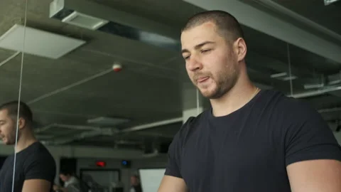 Portrait of an athletic guy with big biceps warming up on a treadmill before a Stock Footage 135591975