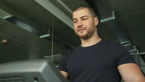 Portrait of an athletic guy with big biceps warming up on a treadmill before a Stock Footage 136813267