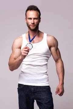 Portrait of athletic man in white undershirt with champions medal Stock Photos