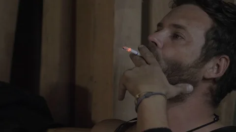 Portrait of an attractive bearded guy with blue eyes who smokes a cigarette Stock Footage 116475064