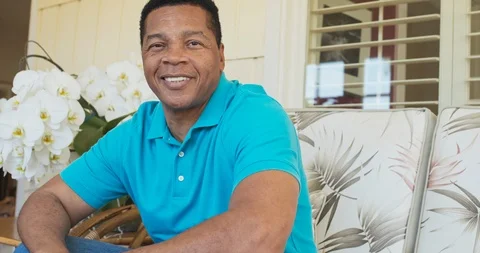 Portrait of attractive Black man smiling and sitting on porch looking at camera Stock Footage 116906574