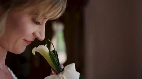 Portrait of attractive bride smiling and sniffing kala flower and look at window Stock Footage 221017154