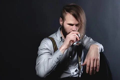 A portrait of an attractive brooding bearded man sitting against a wall lo... Stock Photos