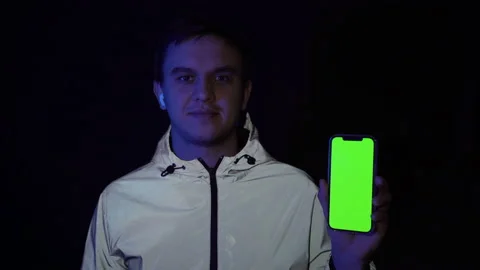 Portrait of an attractive guy in a reflective jacket, having a smartphone with a Stock Footage 150787314