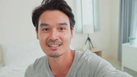 Portrait of attractive male using mobile phone video call in bedroom. Video stock 170876423