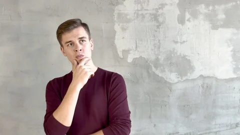 Portrait of attractive man on background of gray wall meditates raises thumbs up Vidéo 119958306