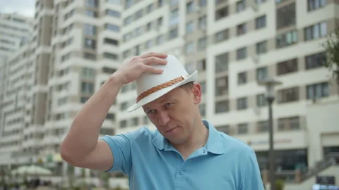 Portrait of attractive man in hat on background of city buildings, camera Stock Footage 155067029