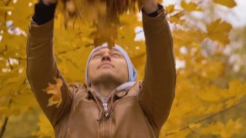 Portrait of an attractive man throws yellow leaves up in the autumn above the Stock Footage 120144946