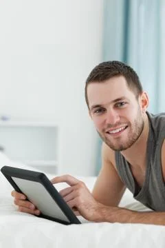 Portrait of an attractive man using a tablet computer while lying on his belly Stock Photos