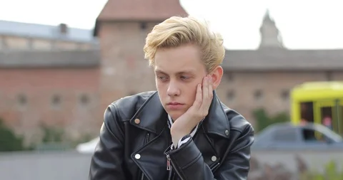 Portrait of attractive sad blond guy sitting and looking straight into camera Stock Footage 126576157