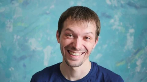 Portrait of attractive smiling men on blue background in slow motion Stock Footage 73936764