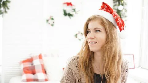 Portrait of attractive smiling woman in Christmas hat at nome Stock Photos