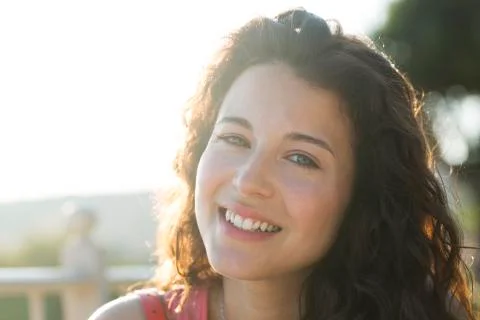 Portrait of an attractive woman smiling to camera with sunlight behind her Stock Photos