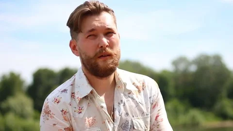 Portrait of attractive young bearded man in shirt looking at the camera outdoors Stock Footage 79649161
