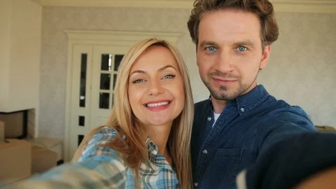 Portrait of attractive young couple making selfie on camera in new house after Stock Footage