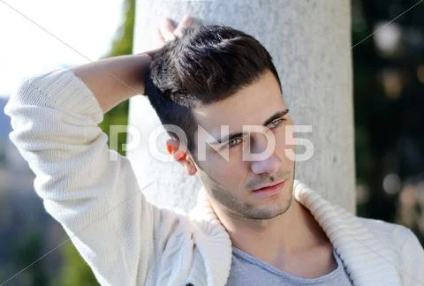 Portrait of attractive young man outdoors against stone pillar Stock Photos