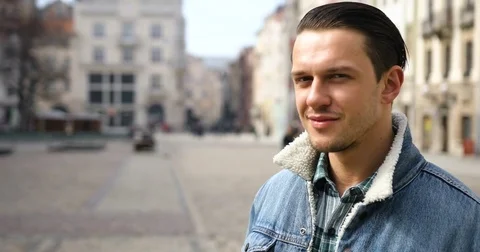 Portrait of an attractive young man turns his head and looks at the camera in Stock Footage