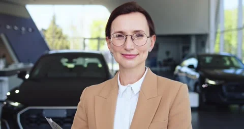Portrait of auto salon representative with glasses holding clipboard and smiling Stock Footage 156539607