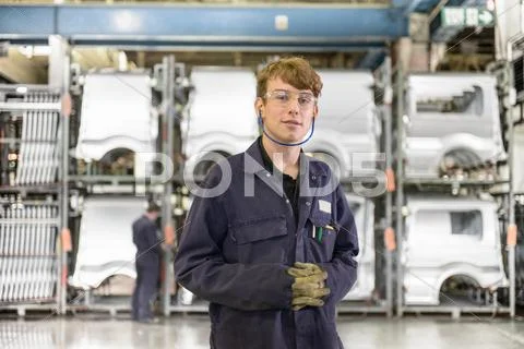 Portrait Of Automotive Apprentice Wearing Boiler Suit And Protective Goggles In